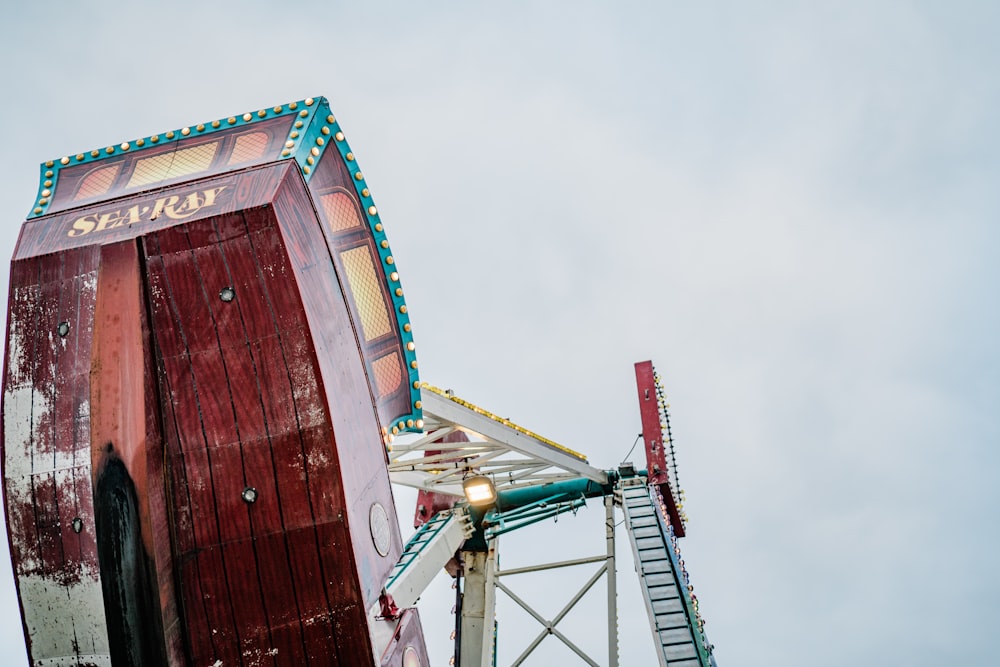 a red and white ferris wheel against a cloudy sky