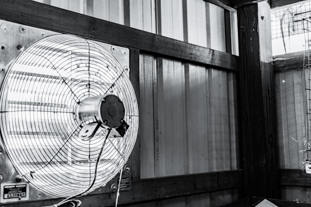 An industrial fan mounted on a brick wall, showcasing sturdy metal construction and powerful airflow.