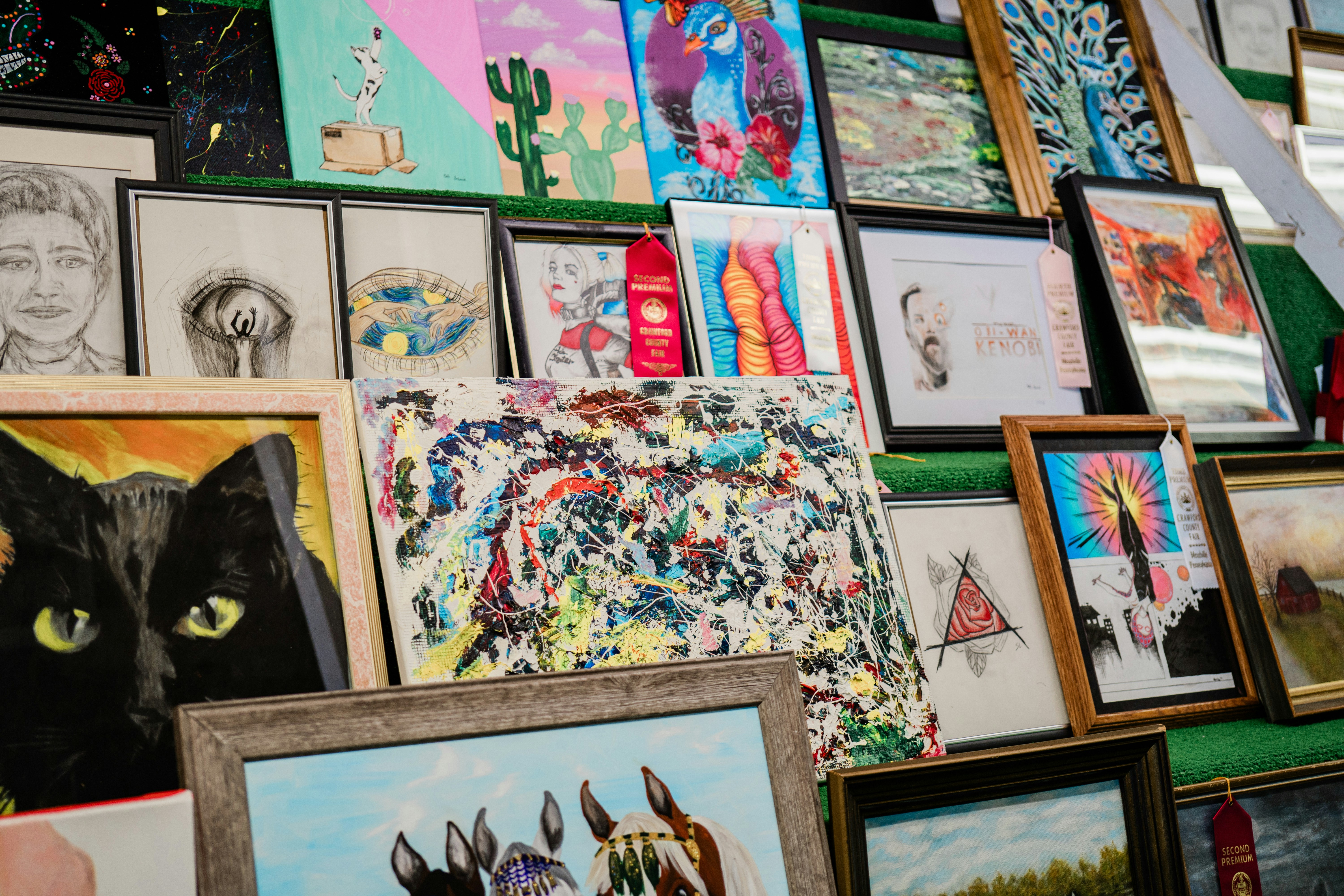 um monte de quadros e pinturas em uma parede