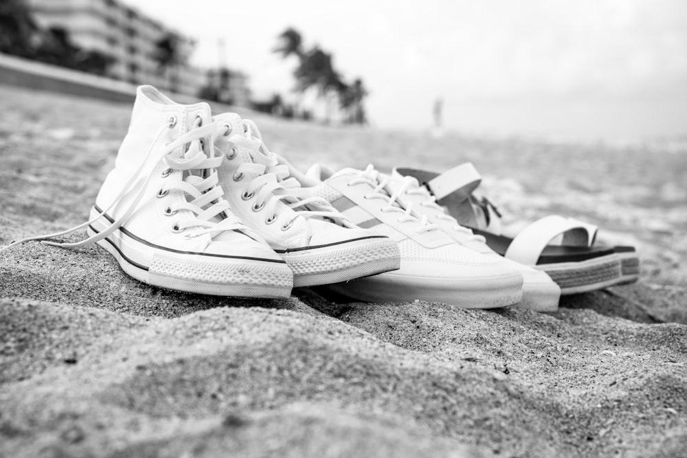 a pair of white shoes sitting on top of a sandy beach