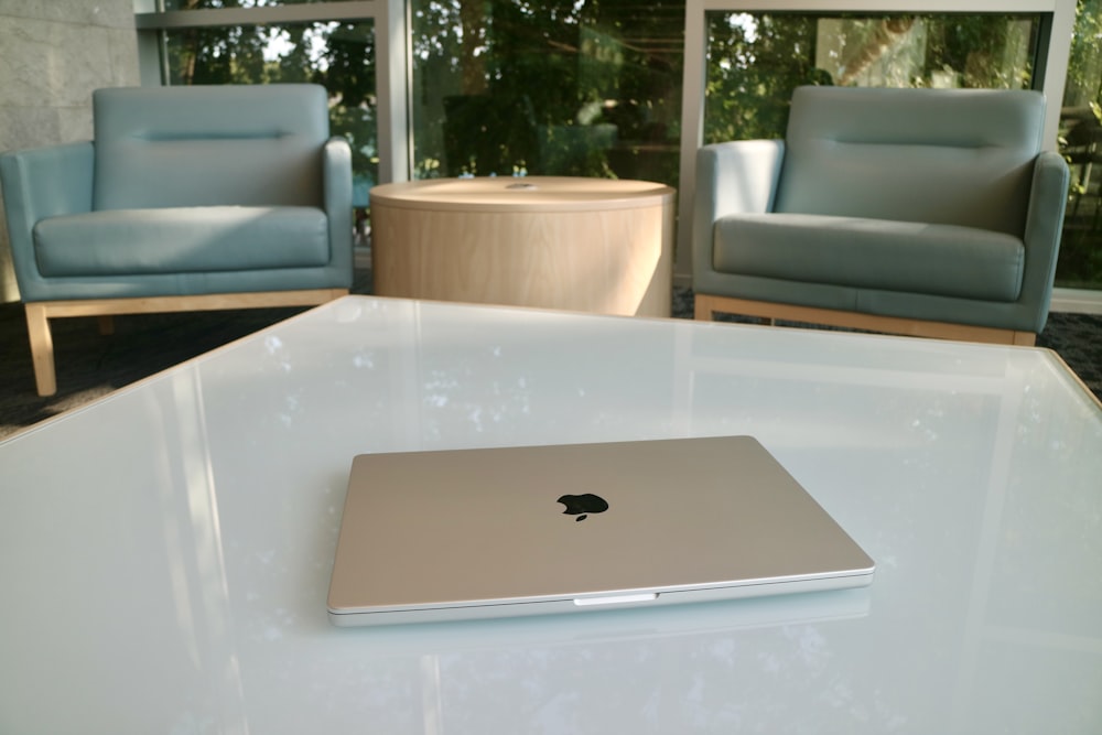 a silver apple laptop sitting on top of a white table