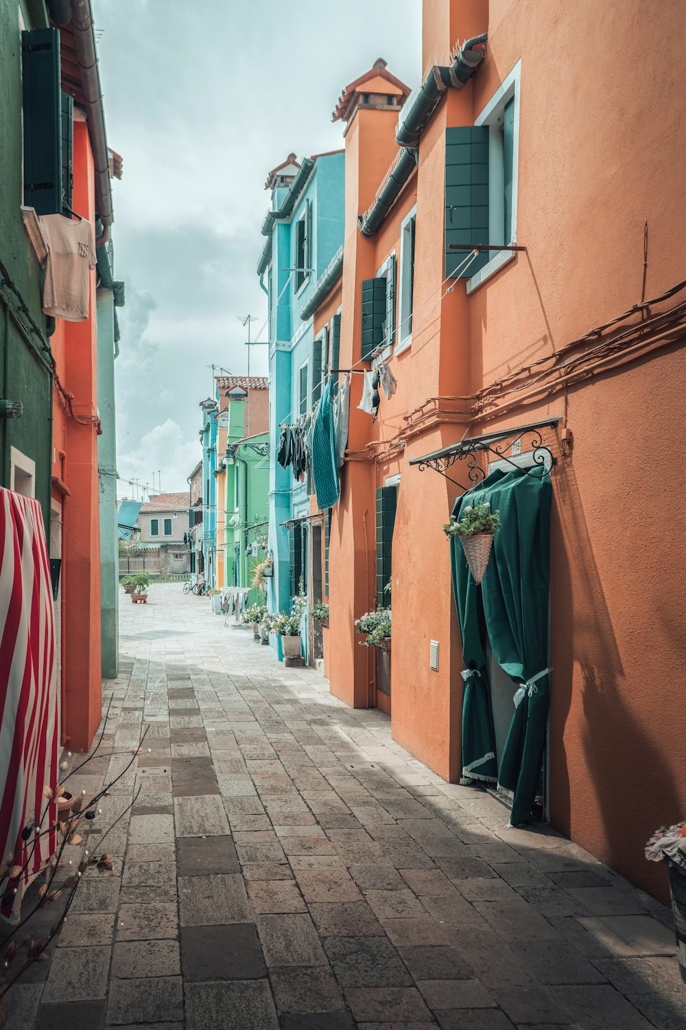 a narrow street lined with colorful buildings and green shutters