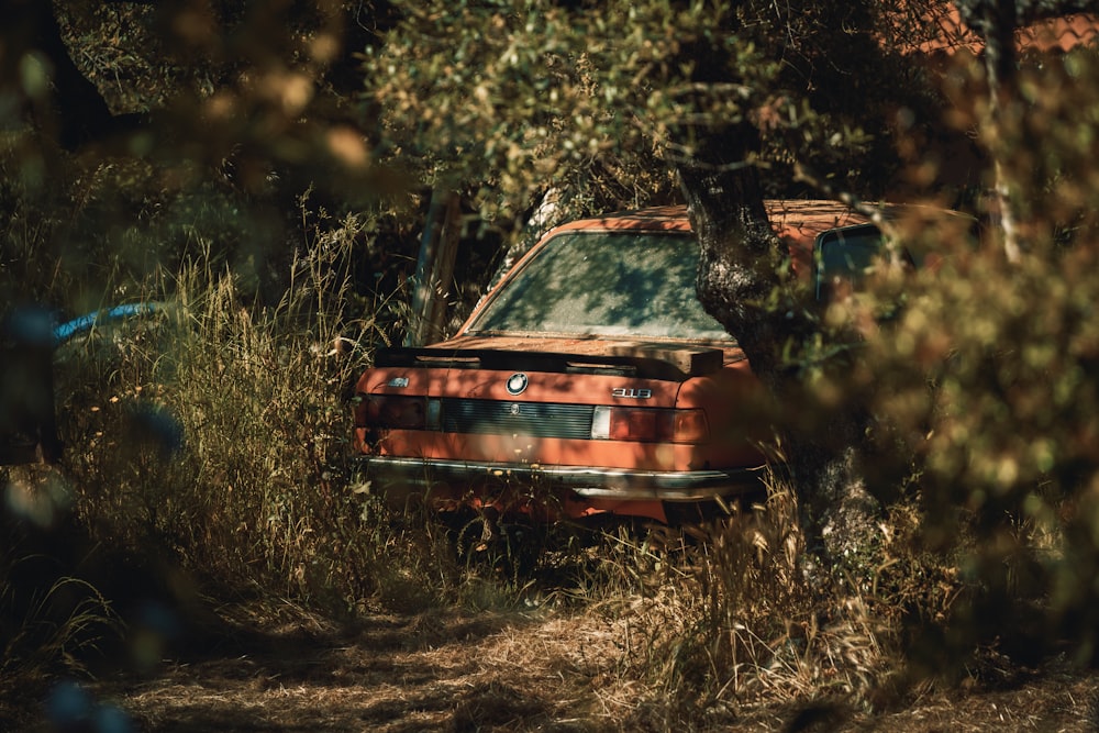 an old rusted out car sitting in the woods