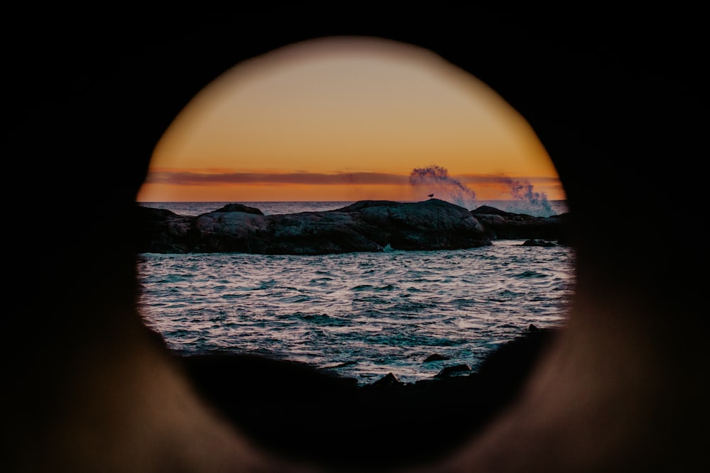 a view of a body of water through a hole in a wall