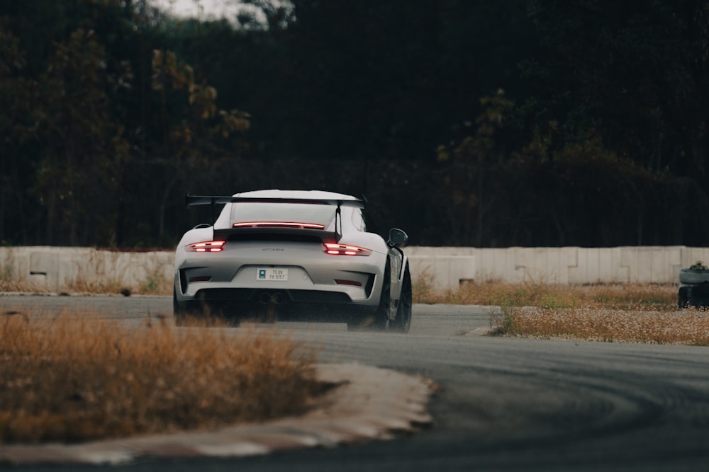a white sports car driving down a winding road