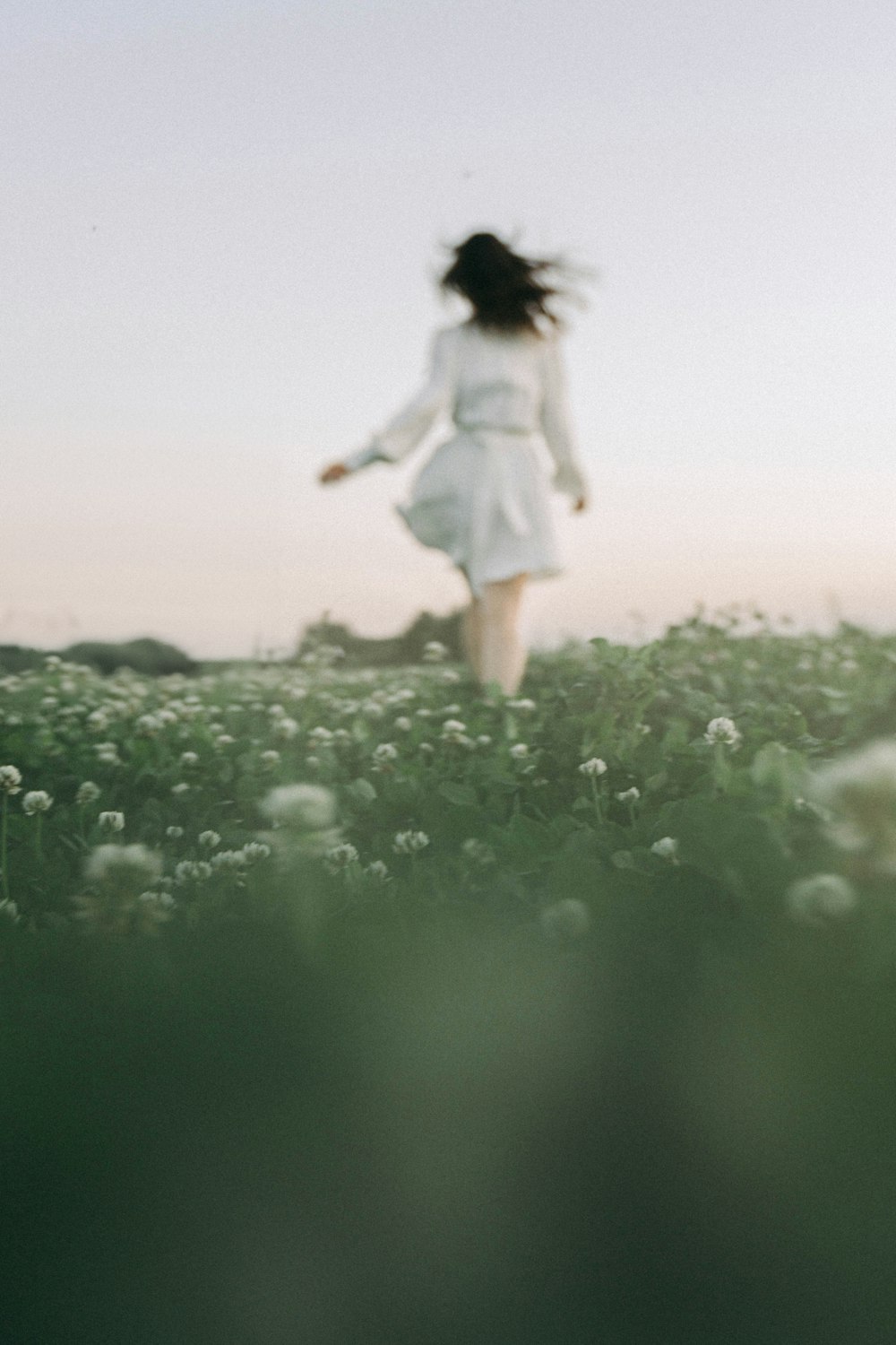 a woman in a white dress walking through a field