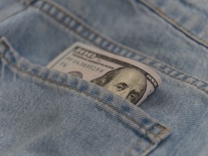 a hundred dollar bill sticking out of the back pocket of a pair of jeans