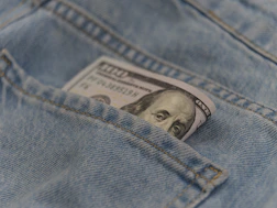 a hundred dollar bill sticking out of the back pocket of a pair of jeans