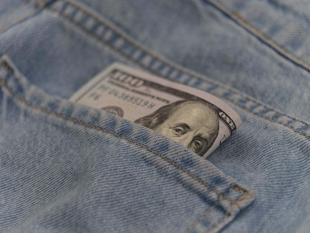 Un billete de cien dólares que sobresale del bolsillo trasero de un par de jeans