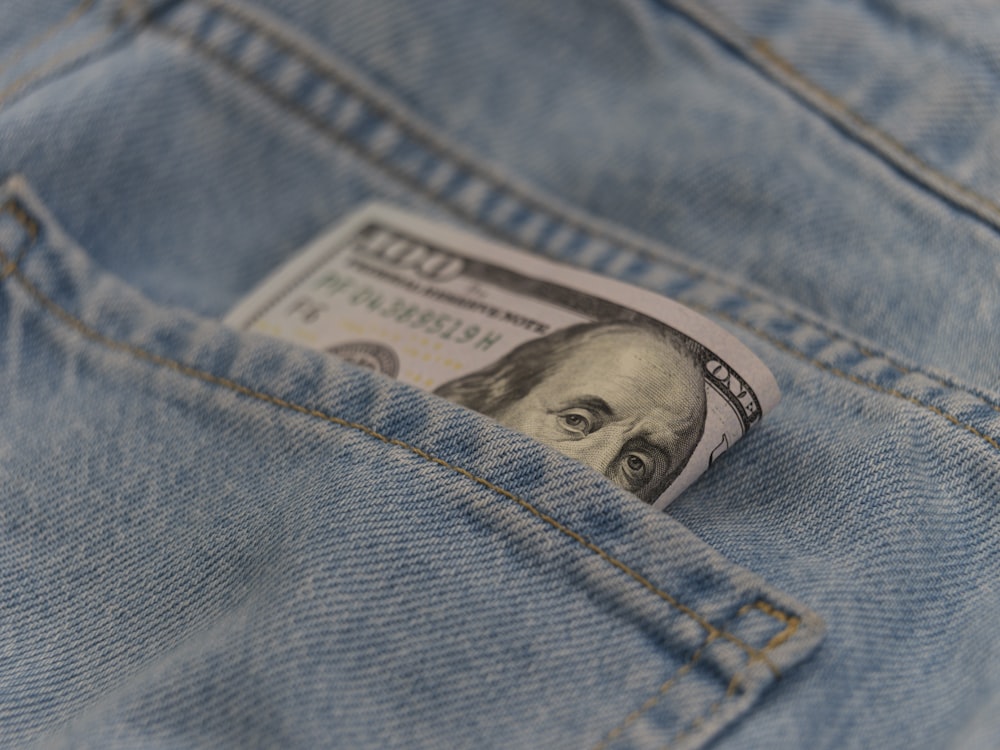 a hundred dollar bill sticking out of the back pocket of a pair of jeans