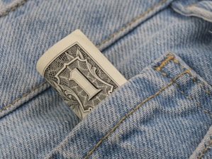 a dollar bill sticking out of the back pocket of a pair of jeans