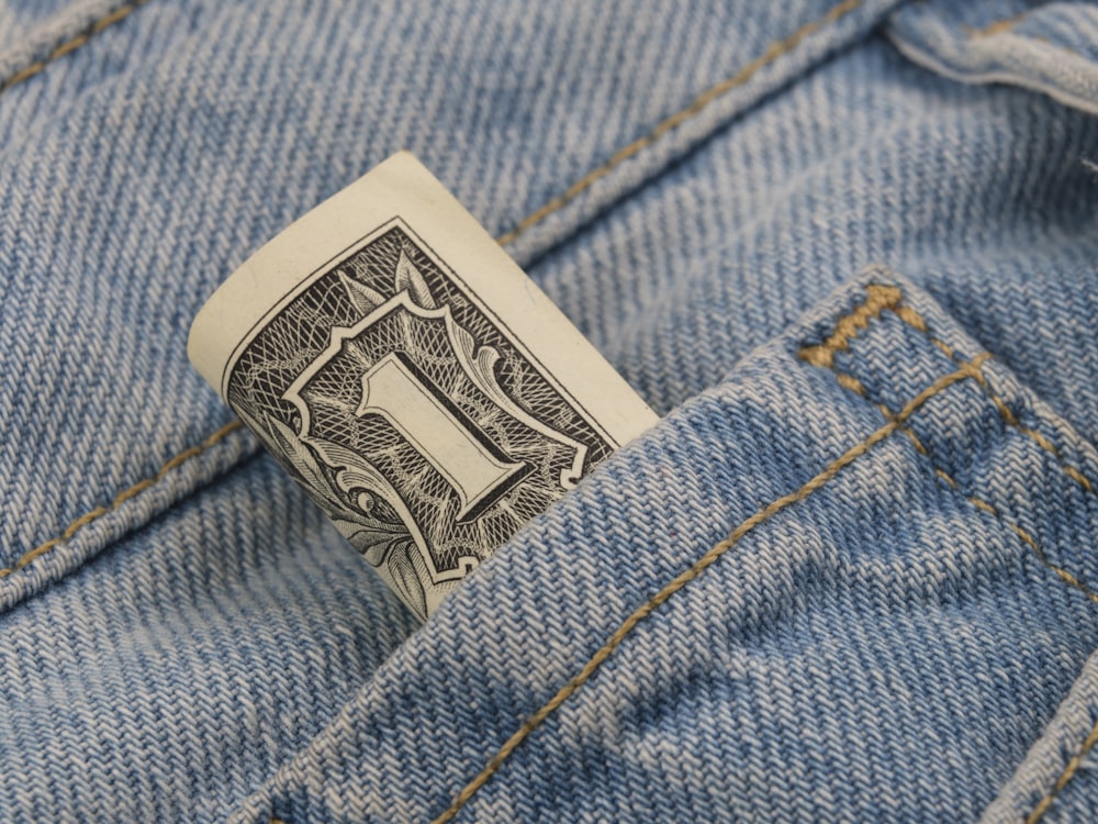 Un billete de un dólar que sobresale del bolsillo trasero de un par de jeans