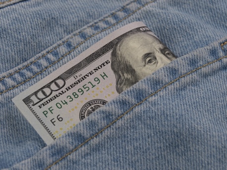 a hundred dollar bill sticking out of the back pocket of a pair of jeans