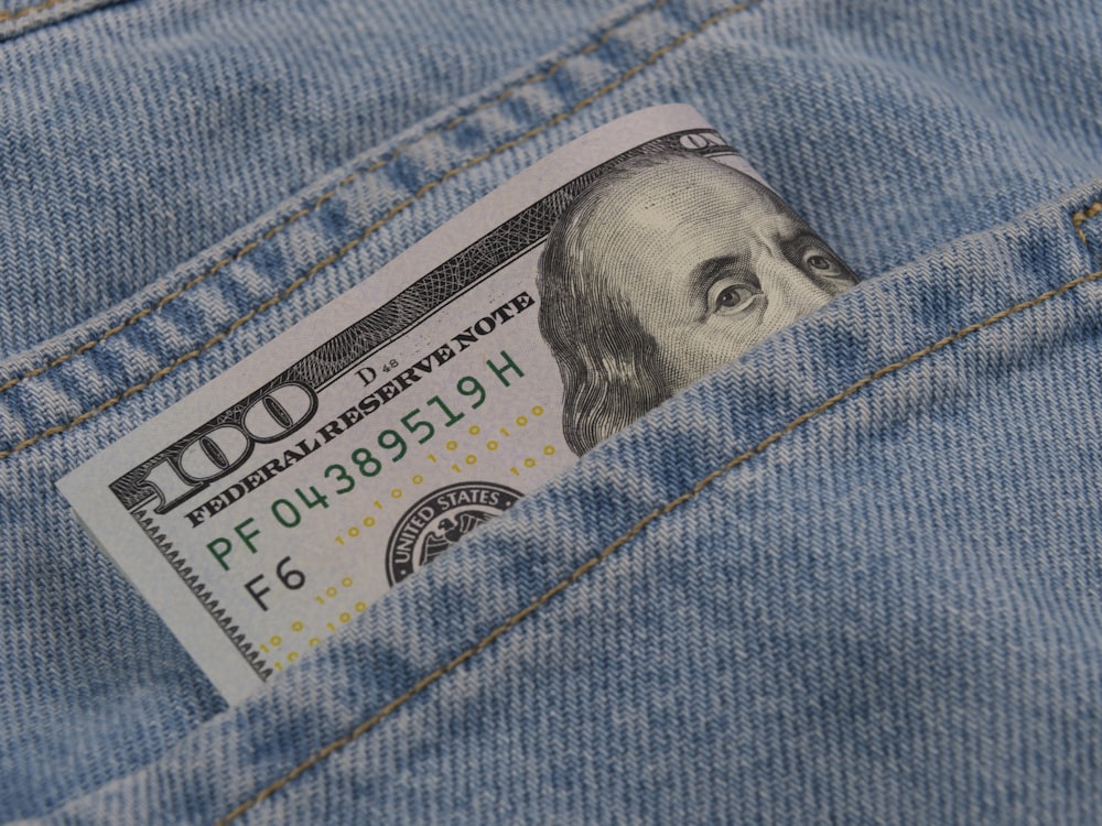 a hundred dollar bill sticking out of the back pocket of a pair of jeans