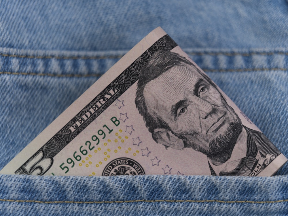 a dollar bill sticking out of the back pocket of a pair of jeans