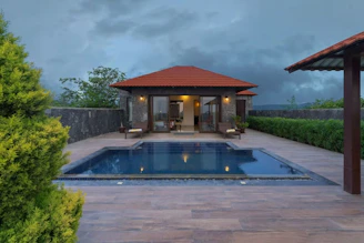 Luxurious modern villa with turquoise pool and ocean view at sunset.