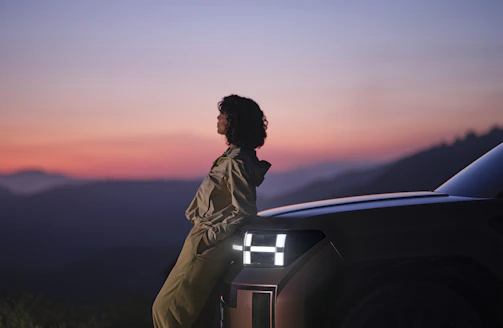 A friendly tow truck driver assisting a customer by their car at sunset