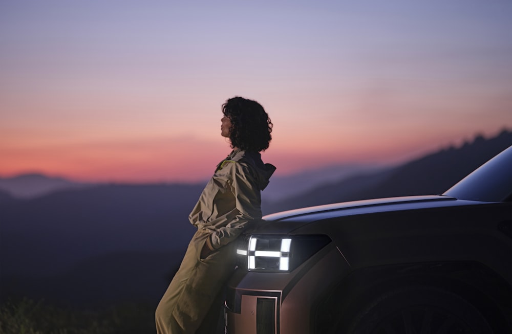 eine frau, die auf der motorhaube eines autos sitzt