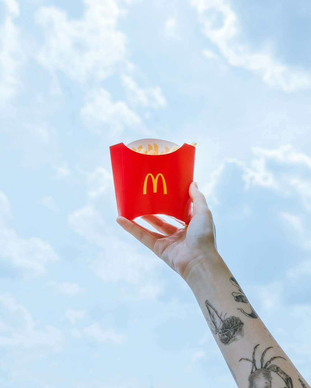 a hand holding a paper container with a mcdonald's logo on it