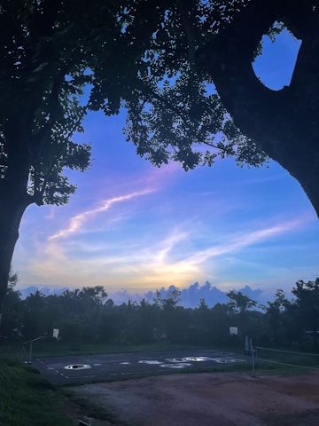 A vibrant basketball court scene with players enjoying a casual game under sunset lighting.