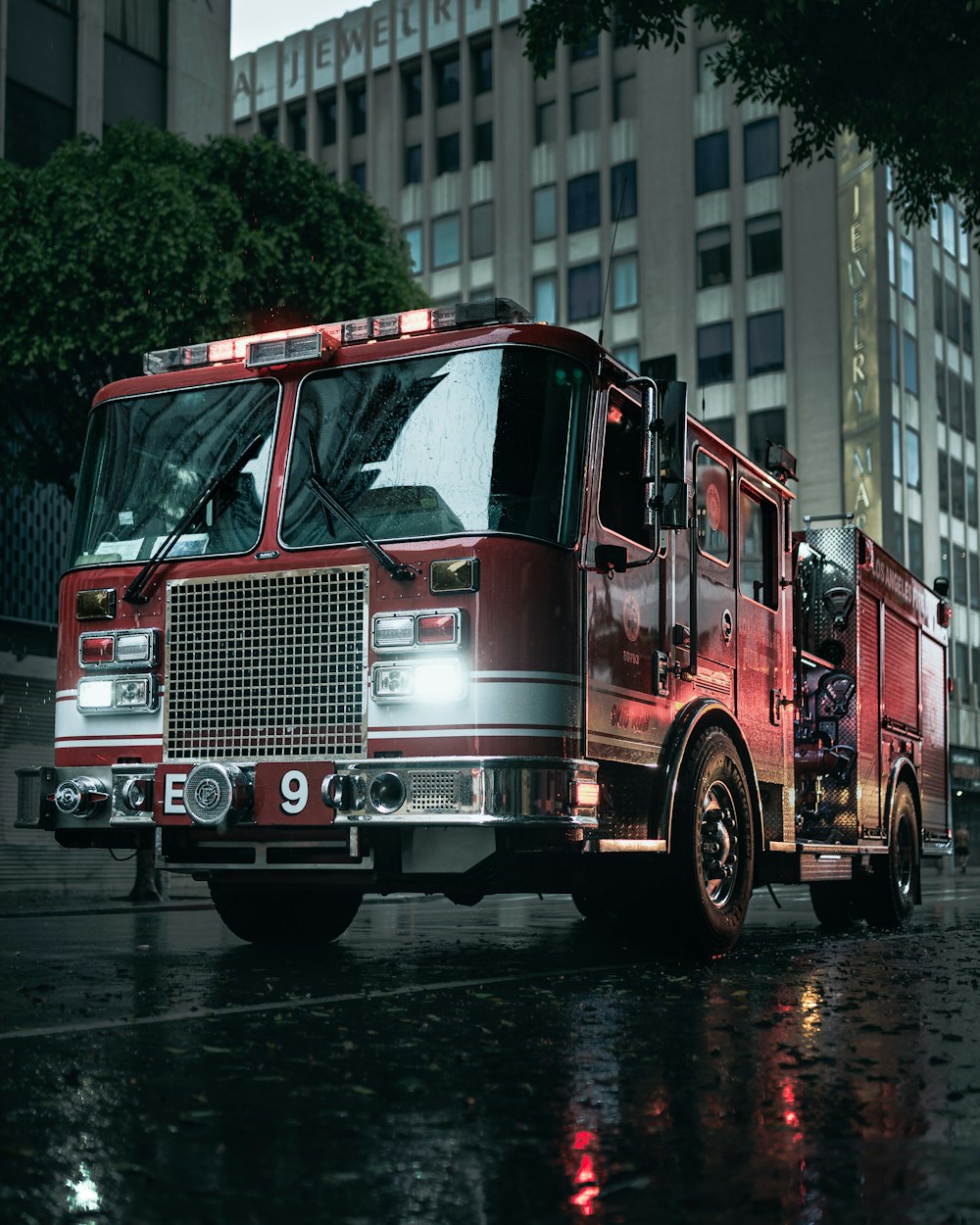 a red fire truck driving down a rain soaked street