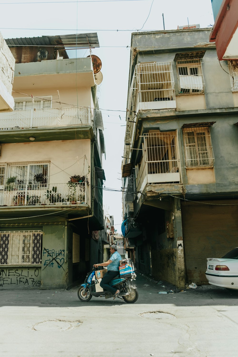 a man riding a motorcycle down a street next to tall buildings