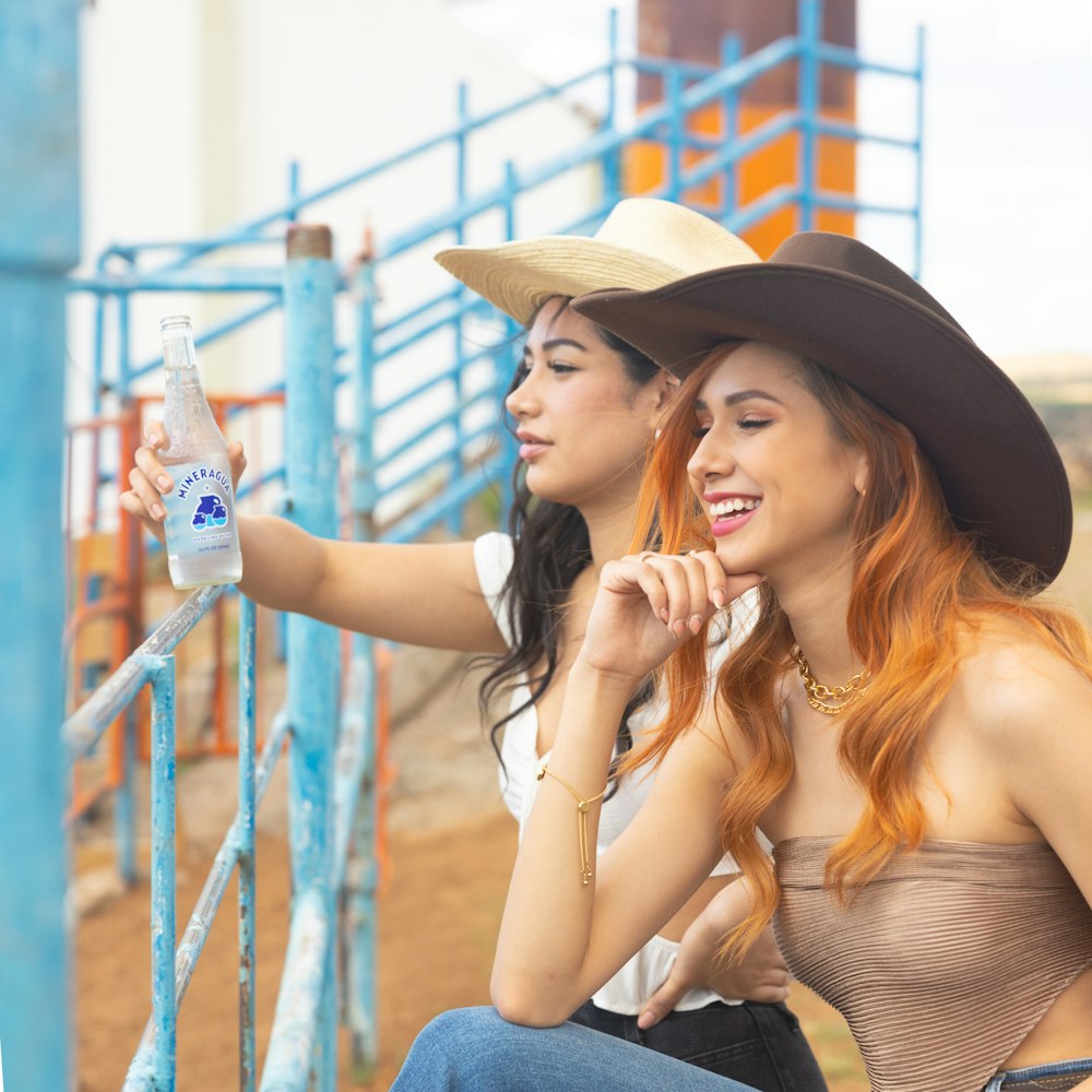 two young women sitting on a blue fence