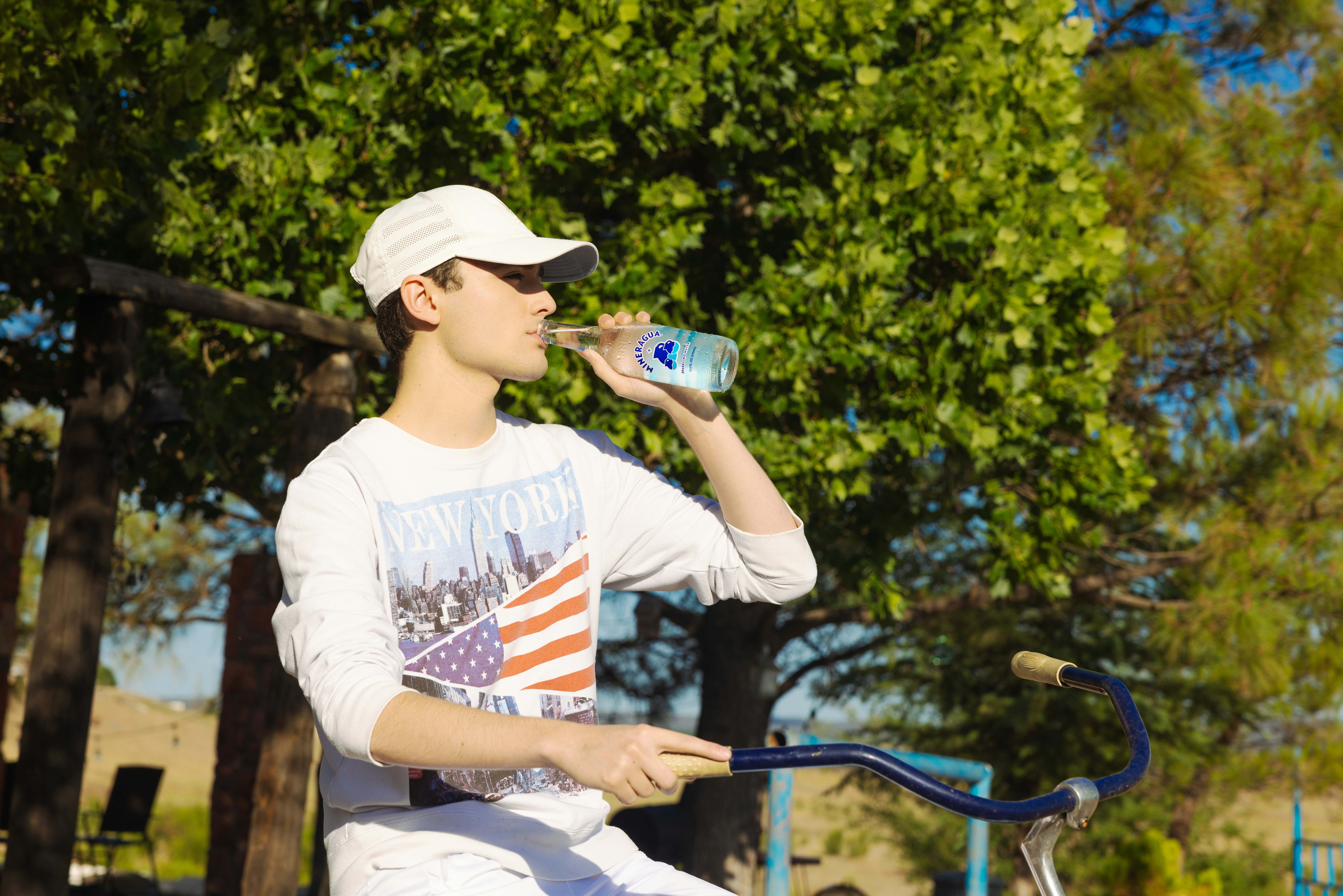 Un giovane seduto su una bicicletta che beve da una lattina