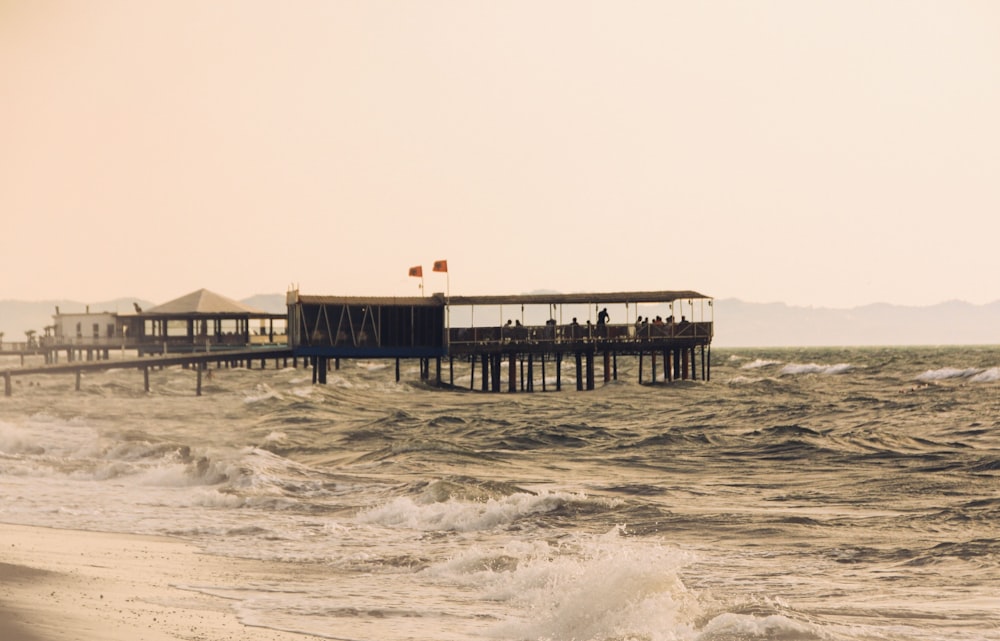 a pier on the beach with people standing on it