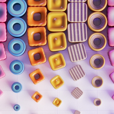 An arrangement of geometrically shaped, colorful 3D objects featuring vibrant colors like pink, blue, orange, and yellow. The objects include rings, squares, and circular shapes with textures ranging from smooth to striped. The composition creates a visually appealing pattern set against a grid-like background.