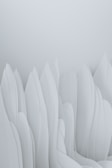 The image features an abstract composition of smooth, flowing forms that resemble elongated, overlapping paper or fabric structures. The soft, pastel tones give the impression of a serene and minimalist landscape.