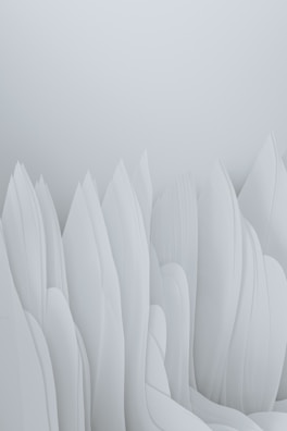 The image features an abstract composition of smooth, flowing forms that resemble elongated, overlapping paper or fabric structures. The soft, pastel tones give the impression of a serene and minimalist landscape.