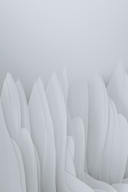 The image features an abstract composition of smooth, flowing forms that resemble elongated, overlapping paper or fabric structures. The soft, pastel tones give the impression of a serene and minimalist landscape.