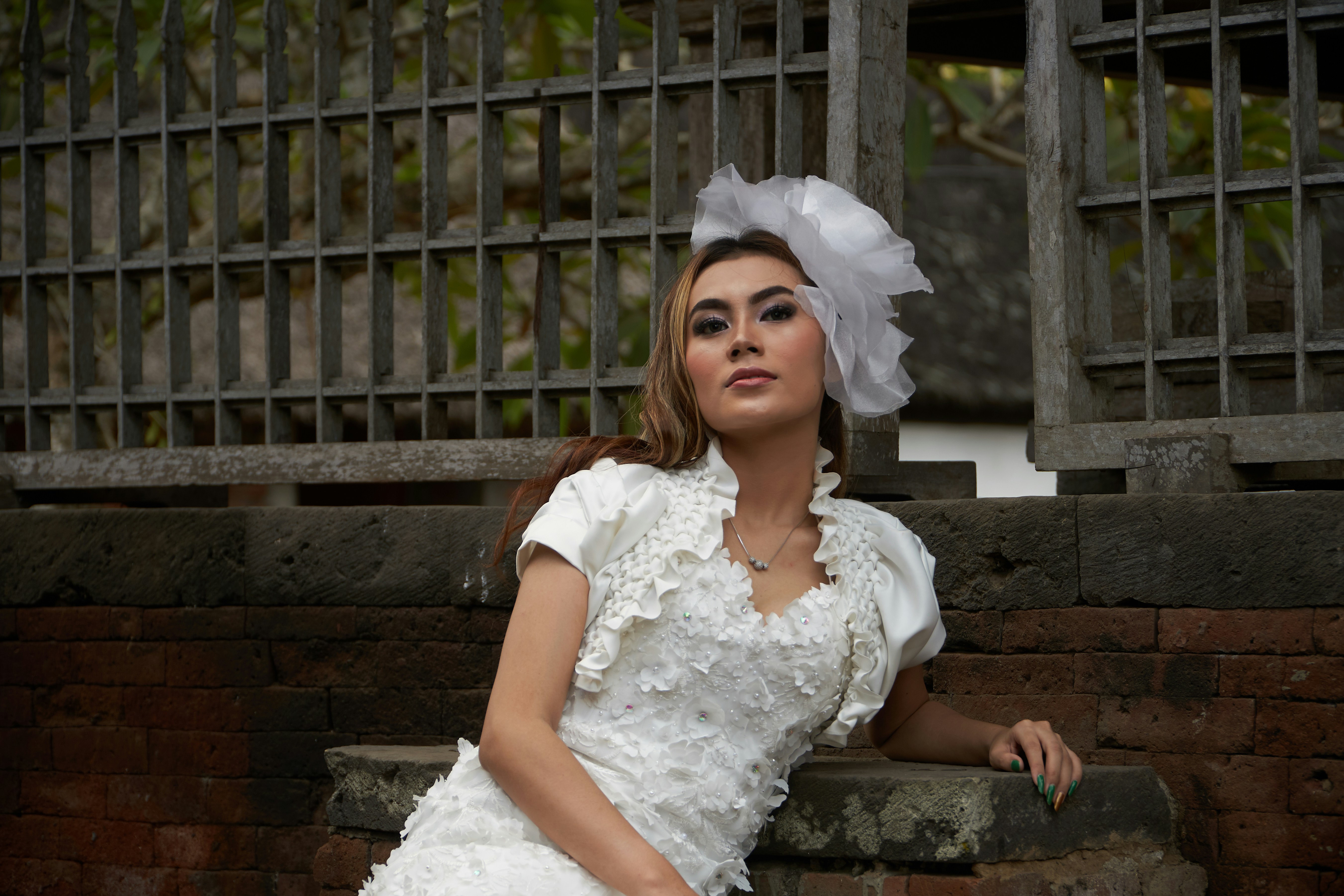a woman in a white dress sitting on a brick wall