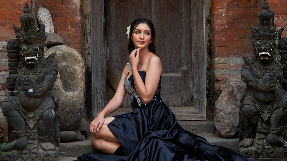 a woman in a black dress sitting in front of a door