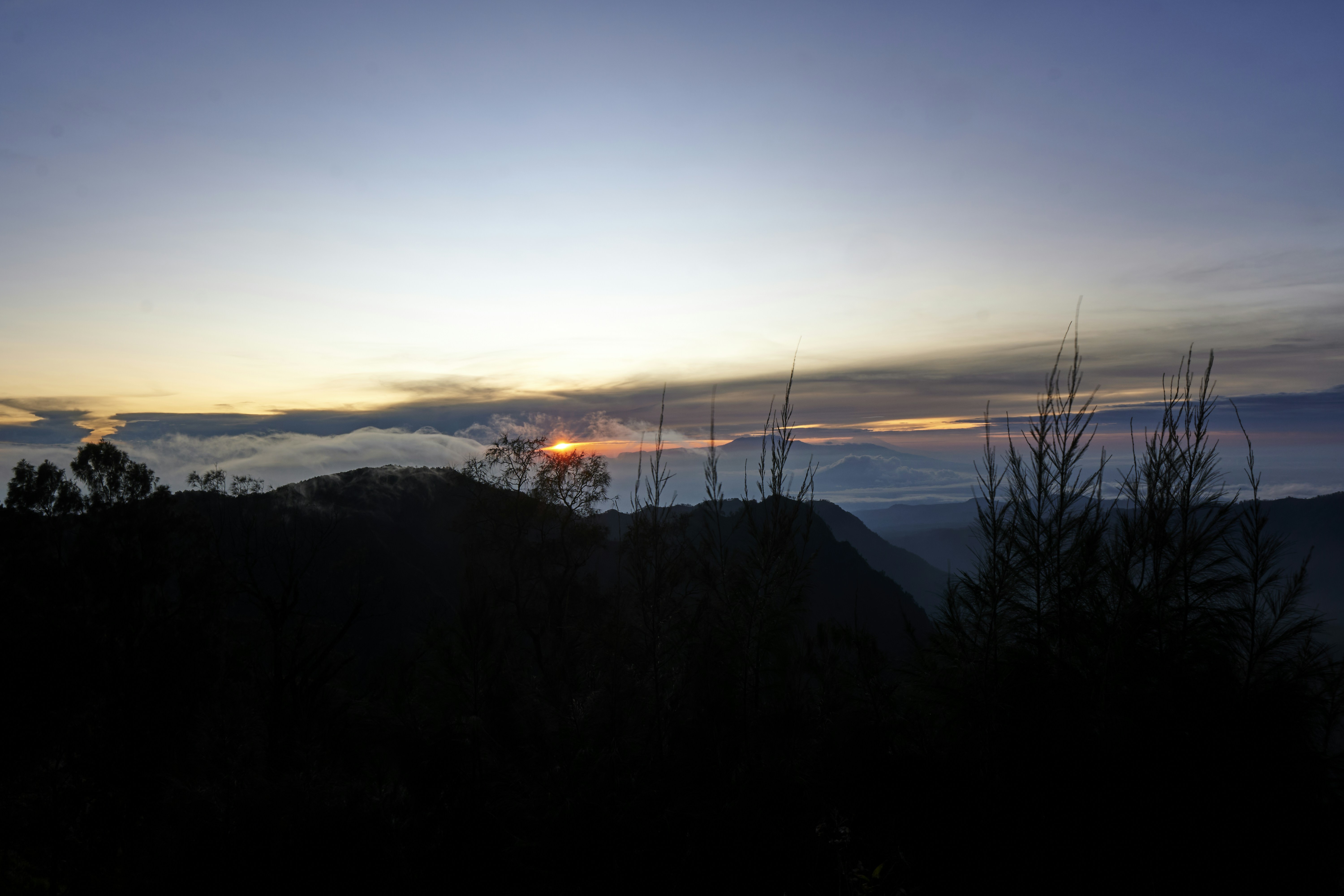 the sun is setting over a mountain range
