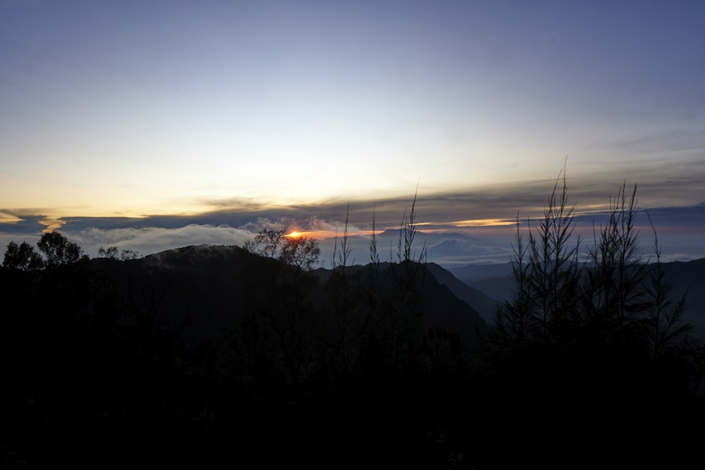 the sun is setting over a mountain range