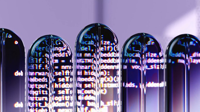 Several test tubes are arranged in a row, reflecting computer code projected onto them. The text appears distorted and split across the test tubes, creating an abstract and futuristic visual effect.