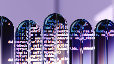 Several test tubes are arranged in a row, reflecting computer code projected onto them. The text appears distorted and split across the test tubes, creating an abstract and futuristic visual effect.