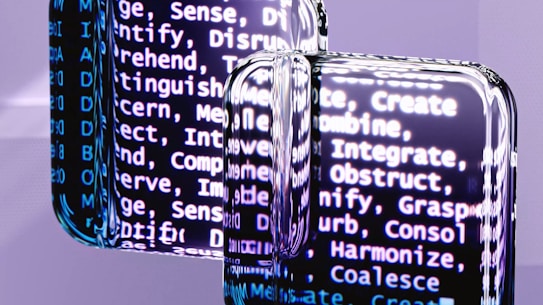 A close-up view of reflective surfaces displaying blurred text with words related to cognitive processes such as create, integrate, and discern. The text is predominantly white and appears on a dark background, creating a high contrast. The reflective surfaces create a distorted and layered effect, adding depth to the image.