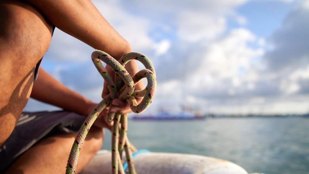 a man sitting on a boat holding a rope