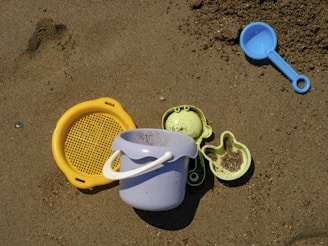 a sand pail and two plastic scoops on a beach