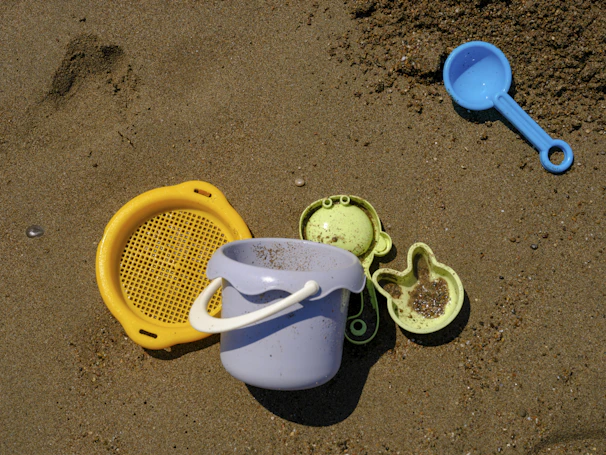 Children playing with colorful beach toys under a bright summer sun.