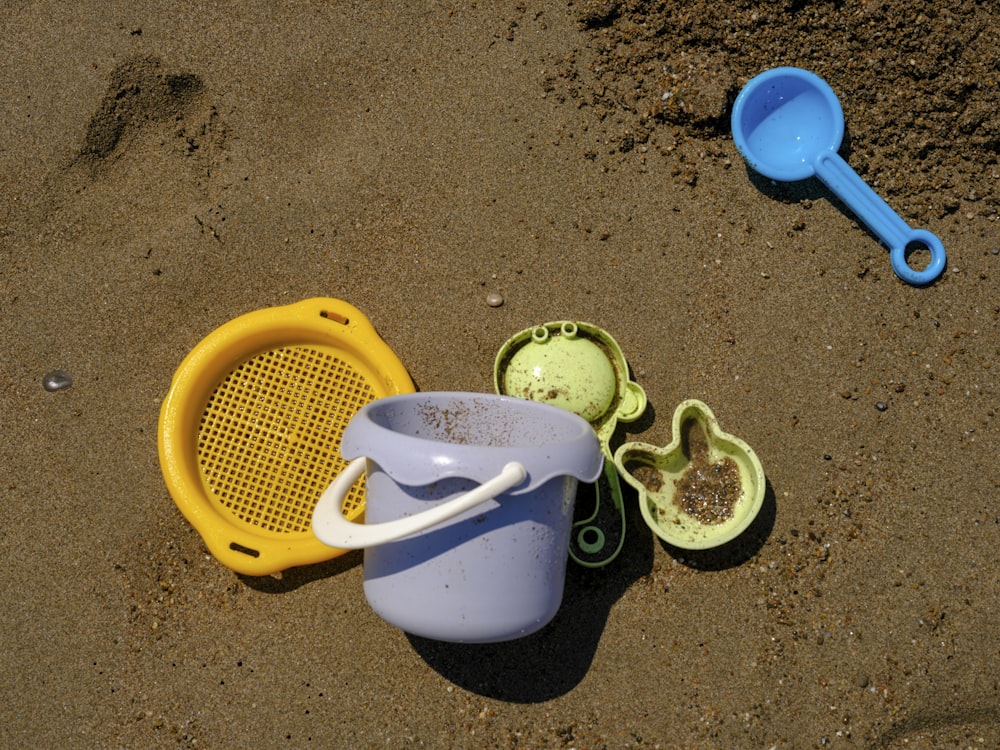 해변에 있는 모래통과 플라스틱 스쿱 두 개
