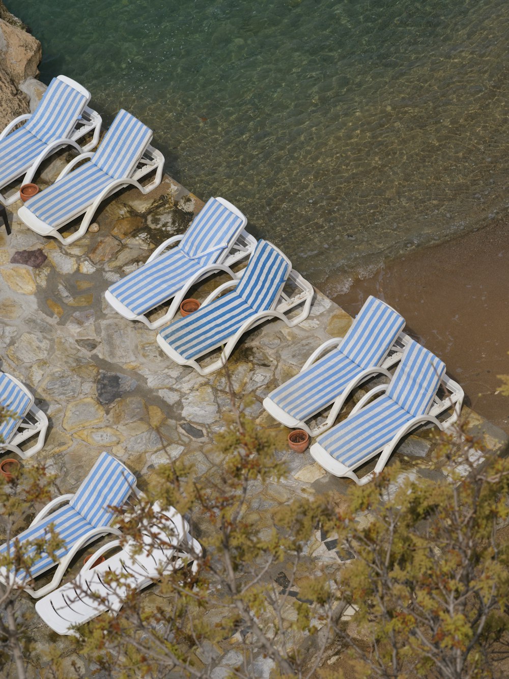 a row of lawn chairs sitting next to a body of water