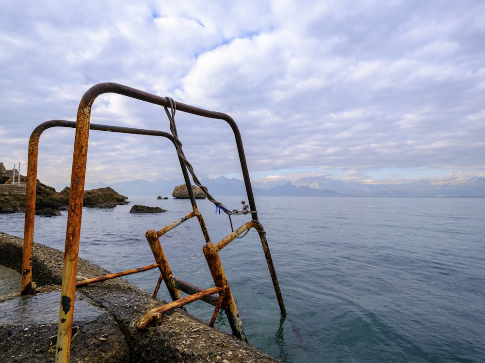 a rusted metal railing on the edge of a body of water