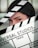 A person wearing a black cap is partially obscured by a film clapperboard. The clapperboard is prominently displaying the text 'Universal Studios' along with scene and take details. The person's eyes are sharply focused.