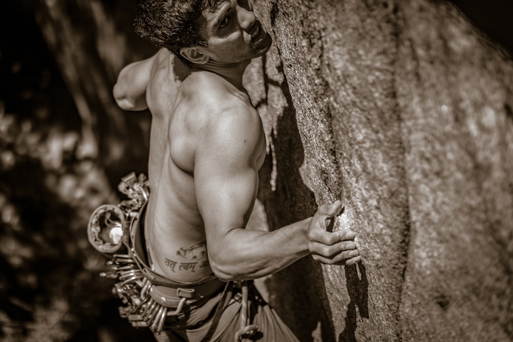 Un uomo che si arrampica sul fianco di una roccia