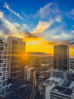 A vibrant sunset over a bustling city skyline captured from a train window