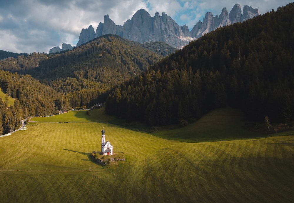 a church in the middle of a field with mountains in the background